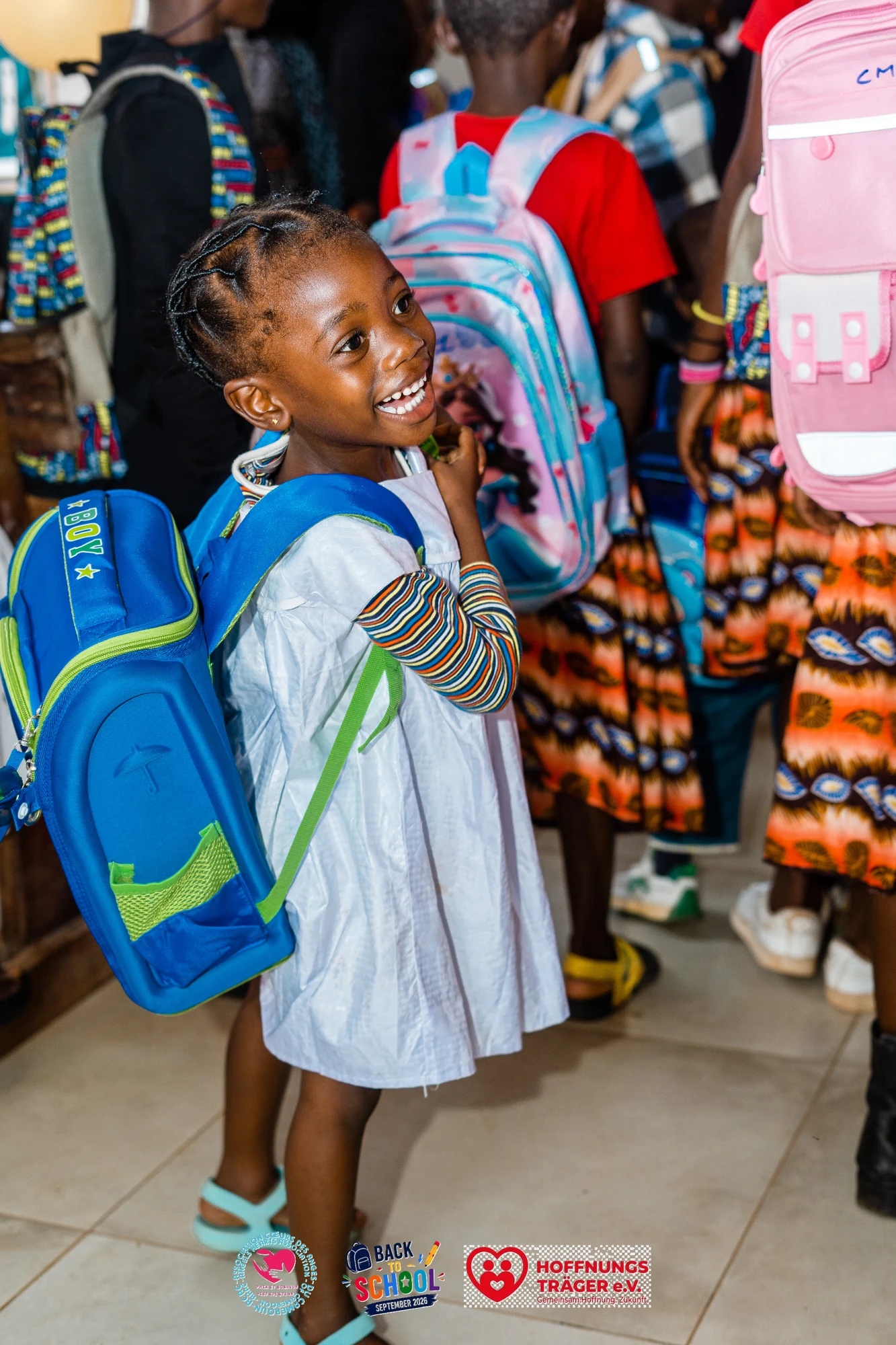 Lächelndes Kind mit blauem Schulrucksack bei der Schulstartaktion in Yaoundé